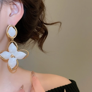 Gros plan d'élégantes boucles d'oreilles fleurs blanches à double couche sur un mannequin