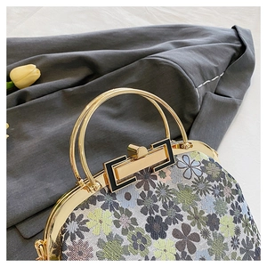 Close-up of vintage shell handbag with floral fabric and gold metal circular handle