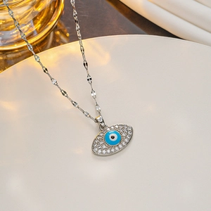 Macro detail of silver evil eye necklace with blue enamel and clear zircon on a tray