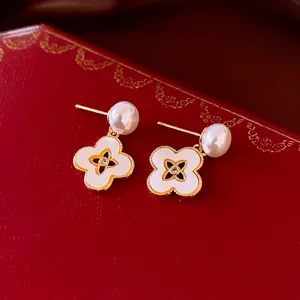 18k gold plated pearl and clover drop earrings on a vintage red jewelry box background