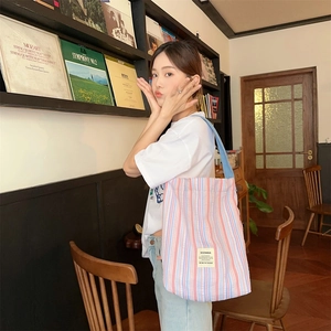 Détail du sac cabas en toile à rayures roses et bleues avec logo de la marque