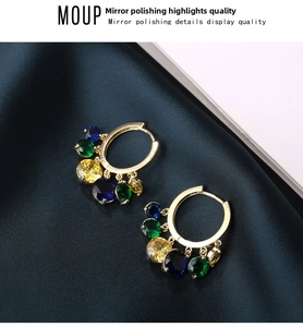 Detail of gold-plated hoop earrings with multi-color crystal charms on blue satin