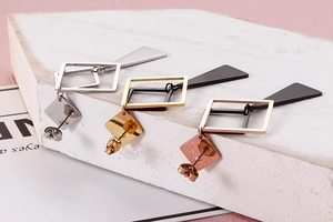 Macro detail of geometric square drop earrings in gold, silver, and rose gold metal finish