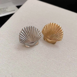 Detailed view of shell-shaped metal ear clips in gold and silver with ribbed texture