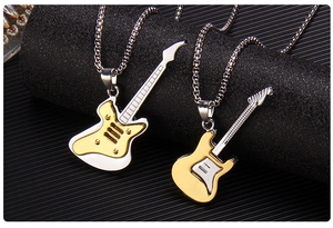 Close-up of gold and silver guitar pendants on metal chains over black texture