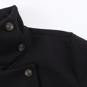 Détail d'une veste courte en laine noire avec des boutons en résine effet marbre