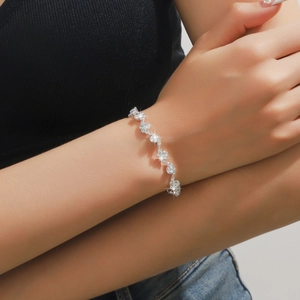 Dettaglio di un bracciale d'argento a onde con zirconi sul polso di una donna