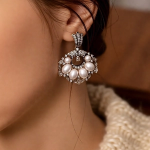 Close-up of vintage drop earrings with pearls and rhinestones on a model's ear