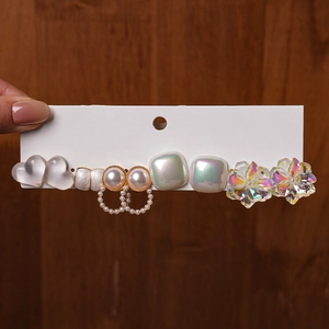 Detail of long hair clip with resin hearts, pearls and iridescent floral charms on a card