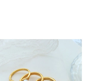 Close-up of gold chain-link rings and a luxury white pearl ring on lace background