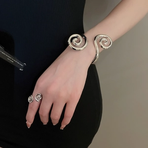 Detailed view of silver spiral bracelet and open ring set with polished mirror finish