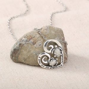 Close-up of silver turtle heart pendant with I love you forever engraving on a stone