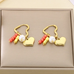Detail of heart hoop earrings with orange beads, white pearls and gold pendants