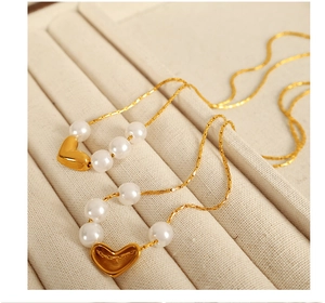 Détail du collier avec pendentif cœur doré et perles blanches dans son écrin à bijoux