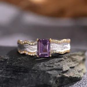 Close-up of rectangle cut purple gemstone ring with wave texture band on dark stone