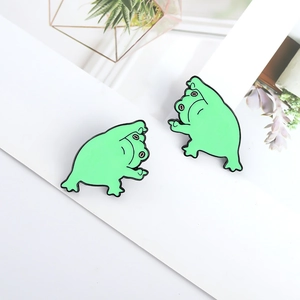 Détail de deux jolis pins en émail de grenouille verte au design de dessin animé vif