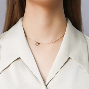 Rose gold titanium steel necklace featuring paper plane and star charms on female model