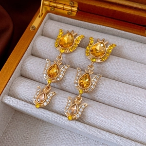 Macro shot of vintage gold tulip earrings with amber crystals in a beige velvet jewelry box