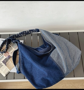 Close-up of denim hobo bag featuring two-tone patchwork and hand-woven rope strap