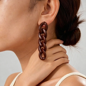 Detail of a large brown acrylic chain earring worn by a model on the left ear