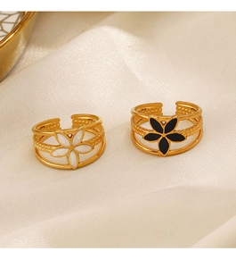 Close-up of 18K gold plated flower rings with black and white enamel on silk fabric
