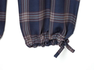 Close-up of the elastic cuff and lace-up drawstring on navy blue plaid cargo pants