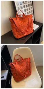 Detail view of orange quilted tote bag featuring adjustable strap and side pockets