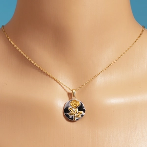 Detail of rose embossed gold and silver pendant on o-chain worn on a model neck