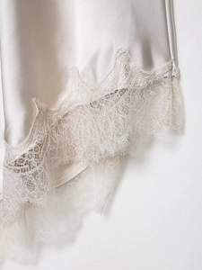 Detail of silk satin dress hem with champagne eyelash lace trim and smooth fabric texture