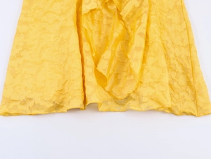 Detail showing the textured yellow fabric hem with elegant ruffles and sheer finish