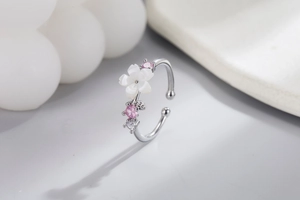 Macro shot of silver flower ring with white shell petals and pink zircon detailing