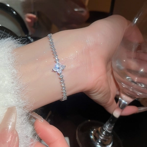 Detailed close-up of a silver bracelet with zircon flowers on a wrist with glint effects