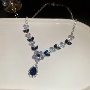 Macro view of flower leaf necklace with marquise zircons and pear-shaped blue gemstone