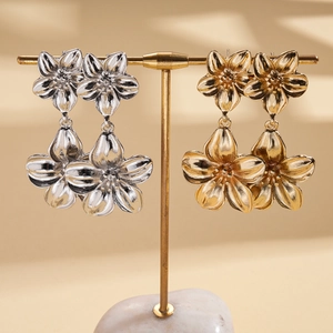 Metallic flower earrings in gold and silver finish on a display stand