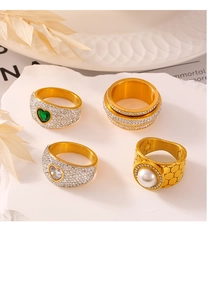 Macro shot of gold-plated rings featuring a green heart stone and a large white pearl