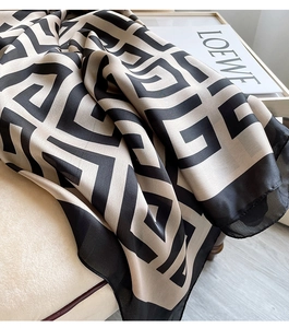 Close-up of houndstooth silk scarf with geometric pattern draped on beige fabric