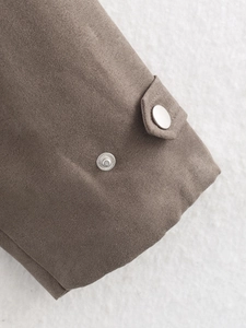 Detailed view of dark brown suede jacket cuff with silver metal snap buttons