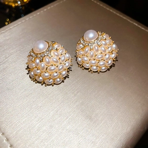 Detail of clusters of faux pearls and white rhinestones on golden floral earrings