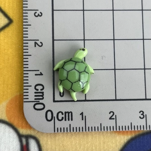 Detailed scale view of a mini green resin sea turtle charm showing 1.5cm dimensions