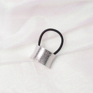 Detailed macro view of a silver matte metal buckle on a black elastic minimalist hair tie