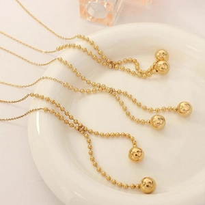 Vintage gold-plated titanium steel bead chain necklaces with polished ball pendants on a tray