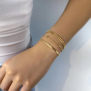 Three-piece gold snake and cuban link bracelet set worn on a model's wrist