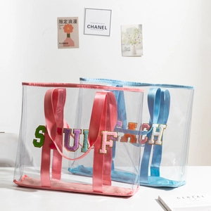 Detail of clear PVC tote bags with colorful STUFF and BEACH towel embroidery letters
