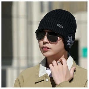 Detail of men's black knit winter hat featuring ear flaps and snowflake pattern