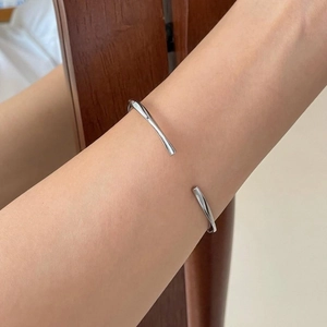 Minimalist silver twist Mobius bangle shown worn on wrist in a lifestyle setting