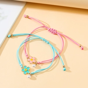 Detail of woven floral bracelets with enamel flower charms and white imitation pearls