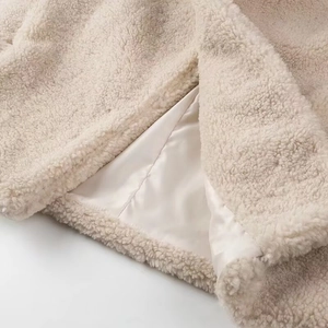 Detail view of smooth cream satin lining and soft faux lamb wool texture on jacket hem