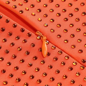 Détail de robe orange côtelée avec strass scintillants et une fermeture éclair invisible
