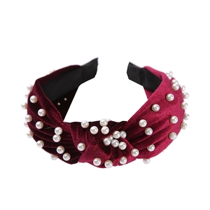 Retro burgundy velvet knotted headband with white pearls on a clean white background