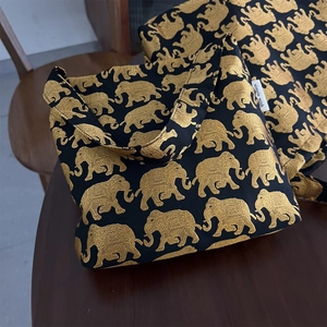 Détail du sac en toile noire avec motifs éléphants dorés et étiquette de marque